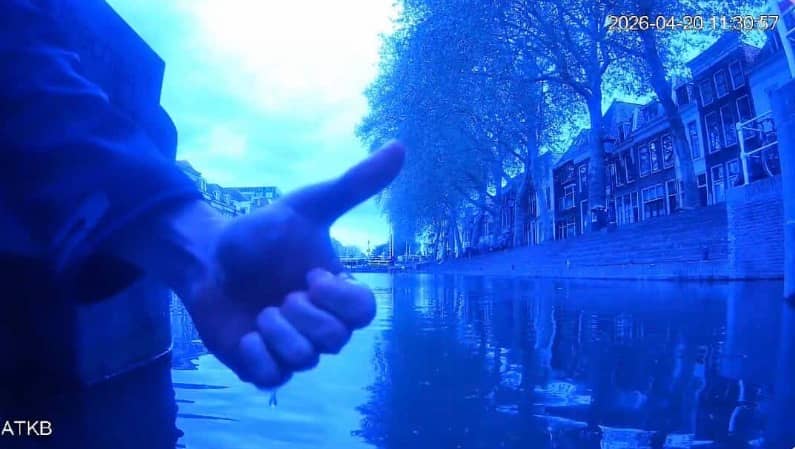 A person gives a thumbs-up beside a Utrecht canal, with the Weertsluis in the background.